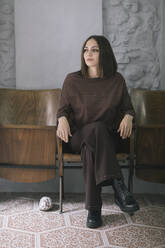 Thoughtful beautiful woman sitting on chair in clothing design studio - ALBF01298