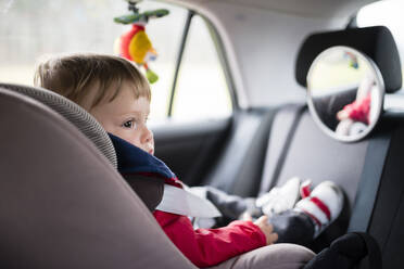 Babyjunge schaut weg, während er auf dem Autositz sitzt - RAEF02397