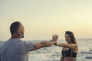 Mature couple touching hands at beach during sunset - DLTSF00755