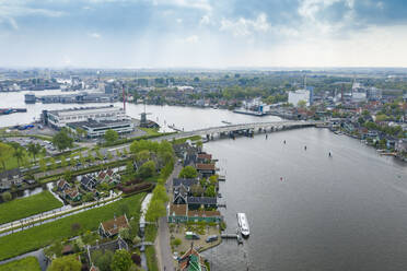 Niederlande, Nordholland, Zaandam, Luftaufnahme der historischen Häuser in Zaanse Schans mit Brücke über den Fluss Zaan im Hintergrund - TAMF02237