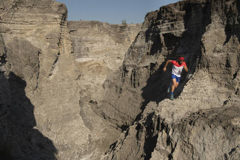 Ein Mann beim Trailrunning auf einem sandigen Terrain aus altem Bergbausand - CAVF84914