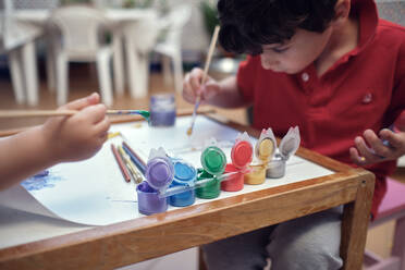 Kinder spielen in einem Innenhof und malen mit Wasserfarben - CAVF84931