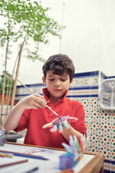 Kinder spielen in einem Innenhof und malen mit Wasserfarben - CAVF84936