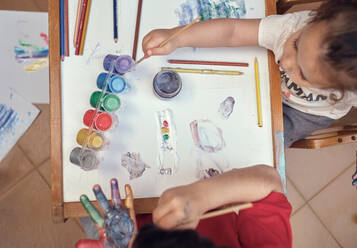 Kinder spielen in einem Innenhof und malen mit Wasserfarben - CAVF84937