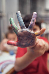 Junge zeigt seine aquarellierte Hand beim Spielen mit seiner Schwester - CAVF84940