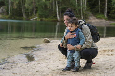 Mutter mit kleinem Jungen schaut beim Wandern am Seeufer weg - CAVF84951