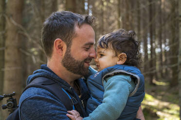 Close-up of smiling father carrying cute son while hiking in for - CAVF84952