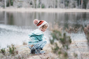 Junges Mädchen sitzt auf einem Felsen und lächelt beim Wandern in Schweden - CAVF84972