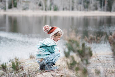 Young girl sitting on a rock smiling whilst hiking in Sweden - CAVF84972