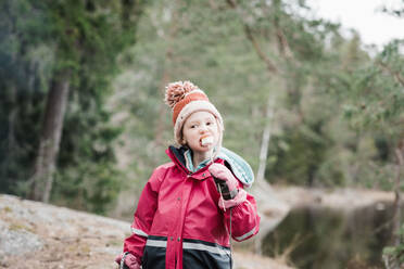 Young girl eating marshmallows whilst camping in a forest in Sweden - CAVF84986