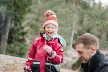 Young girl smiling whist eating a marshmallow whilst camping in Sweden - CAVF84987