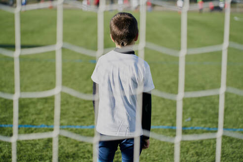 Rear view behind the net of a child football goalkeeper in the goal - CAVF85001