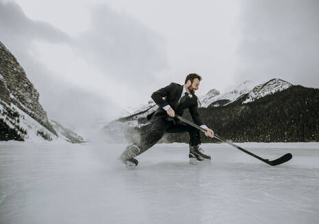 Eishockeyspieler auf gefrorenem See im Anzug hält schnell an und spritzt Eis - CAVF85022