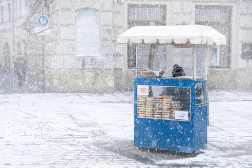 Traditioneller Krakauer Bagel-Verkäufer im Schnee auf dem Stadtplatz, Krakau, Polen, Europa - RHPLF15361