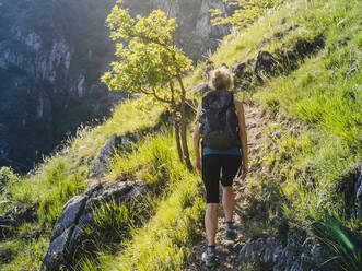 Frau mit Rucksack beim Wandern auf einem Bergpfad, Lecco, Italien - MCVF00432