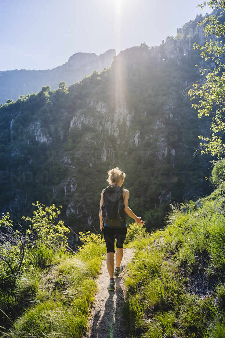 Woman hiking through mountain trail on a sunny day