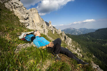 Männlicher Wanderer auf dem Berg Grignetta liegend gegen den Himmel, Europäische Alpen, Lecco, Italien - MCVF00437
