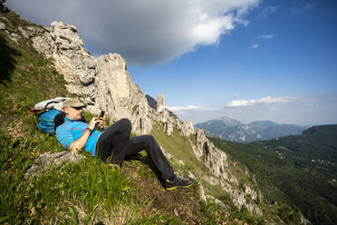 Mann liegend auf dem Berg Grignetta gegen den Himmel, Europäische Alpen, Lecco, Italien - MCVF00438