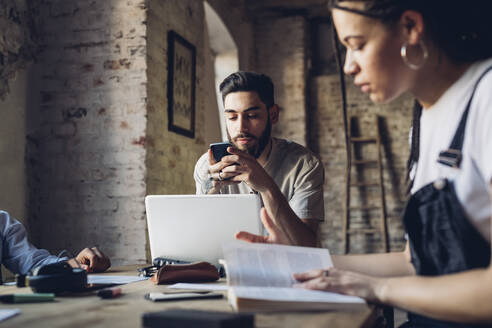 Kreative Geschäftsleute arbeiten an einem Tisch in einem Loft-Büro - MEUF00654