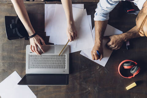 Zwei kreative Geschäftsleute arbeiten mit Laptop und Papieren auf einem Holztisch, lizenzfreies Stockfoto