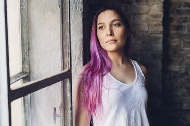 Porträt einer stilvollen jungen Frau mit rosa Haaren in einem Loft - MEUF00680