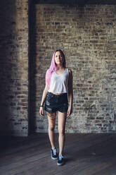 Porträt einer stilvollen jungen Frau mit rosa Haaren in einem Loft stehend - MEUF00681
