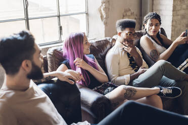 Group of friends sitting on sofa in a loft - MEUF00701