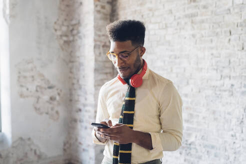 Stilvoller junger Mann benutzt Smartphone im Loft - MEUF00711