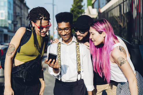 Eine Gruppe von Freunden teilt sich ein Smartphone in der Stadt - MEUF00769