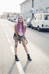 Portrait of a stylish young woman with pink hair standing on the street in the city - MEUF00774