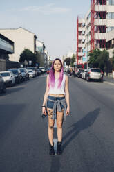 Portrait of a stylish young woman with pink hair standing on the street in the city - MEUF00775