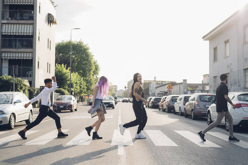 Gruppe von Freunden beim Überqueren einer Straße in der Stadt - MEUF00784