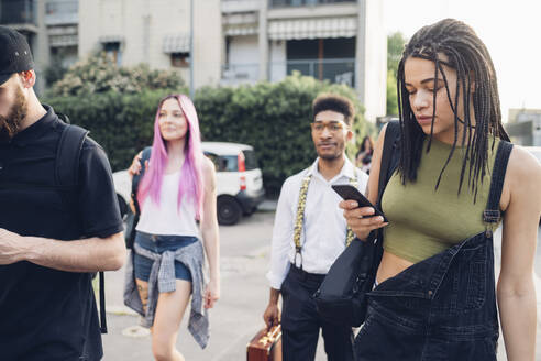 Eine Gruppe von Freunden benutzt Smartphones in der Stadt - MEUF00800