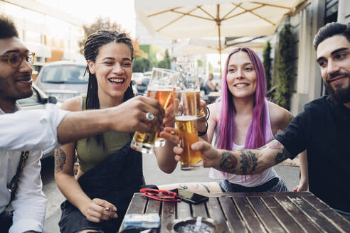 Glückliche Freunde stoßen an einer Bar im Freien mit Biergläsern an - MEUF00803