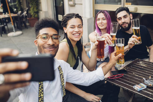 Glückliche Freunde, die Biergläser halten und ein Selfie in einer Bar machen - MEUF00804