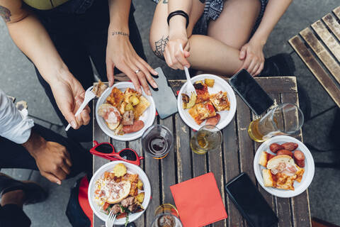 Freunde sitzen am Tisch im Freien und essen Snacks, lizenzfreies Stockfoto