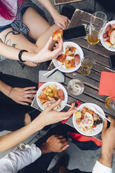 Freunde sitzen am Tisch im Freien und essen Snacks - MEUF00812