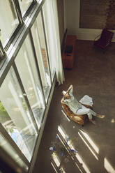 Älterer Mann entspannt sich auf einem Stuhl in einer Dachgeschosswohnung - MCF00996