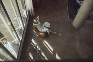 Älterer Mann entspannt sich auf einem Stuhl in einer Dachgeschosswohnung - MCF00999