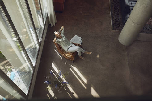 Senior man relaxing on a chair in a loft flat - MCF00999