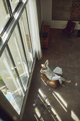 Älterer Mann entspannt sich auf einem Stuhl in einer Dachgeschosswohnung - MCF01002