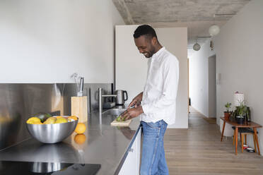 Smiling man slicing avocado in kitchen - AHSF02750