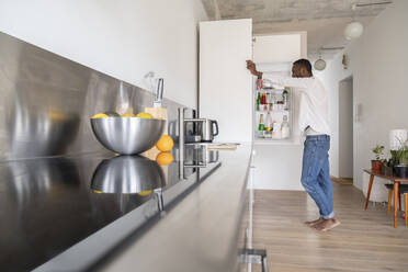 Man standing in the kitchen looking into fridge - AHSF02752