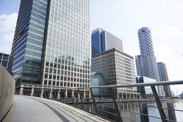 Großbritannien, England, London, Leere Brücke in den Londoner Docklands mit Wolkenkratzern im Hintergrund - PMF01087