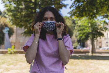 Mature woman wearing protective face mask in city during COVID-19 - FMOF00995