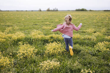 Girl in yellow rubber boots running near rape field - EYAF01123