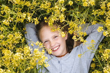 smiling girl lying in rape flowers - EYAF01126