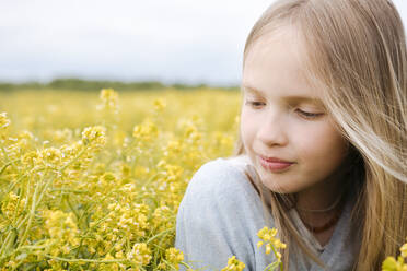 Portrait of girl looking at rape flowers - EYAF01127