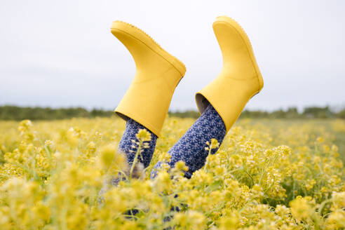 Girl's legs in yellow rubber boots in rape field - EYAF01128