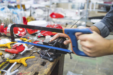 Man working with saw on fencing weapon on workbench - MEUF00879